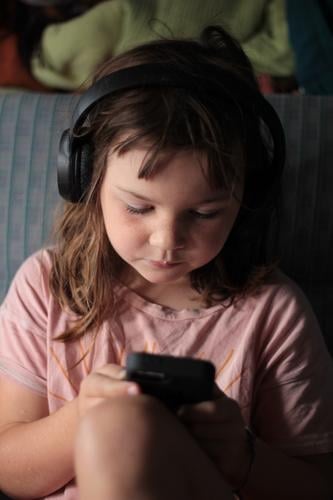 Looking for an audio book Digital Child Girl Computer Cellphone mobile Typing Tray wireless headphones Pink T-shirt Bus vacation Rear seat secluded Car seat