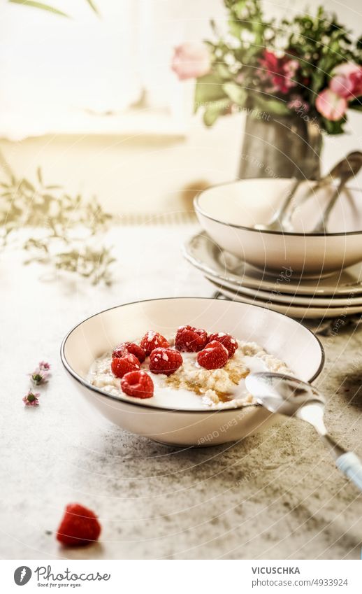 Breakfast porridge bowl with raspberries on table at window background breakfast food homemade health cereal spoon morning sweet berry red fruit oatmeal diet
