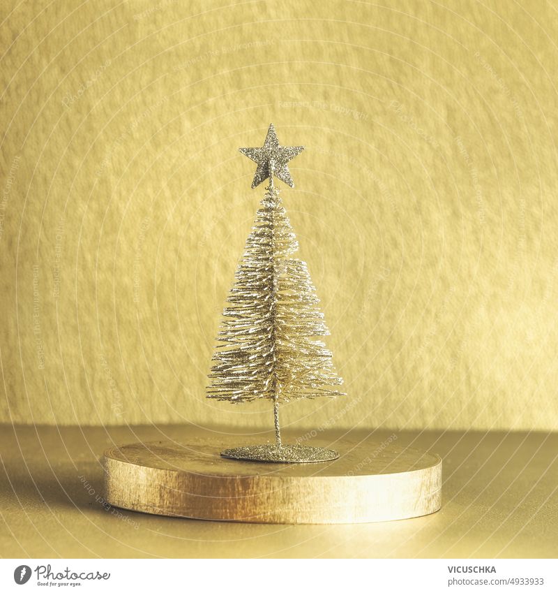 Golden Christmas tree on podium. Seasonal modern winter and new years backdrop. golden christmas tree seasonal festive decor front view background celebration