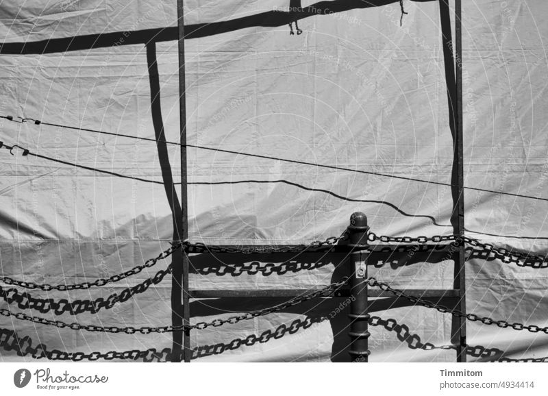 Behind it a construction site Construction site Shielding tarpaulin crease Safety Pole chains rods poles Aspire Black & white photo Light Shadow Cologne