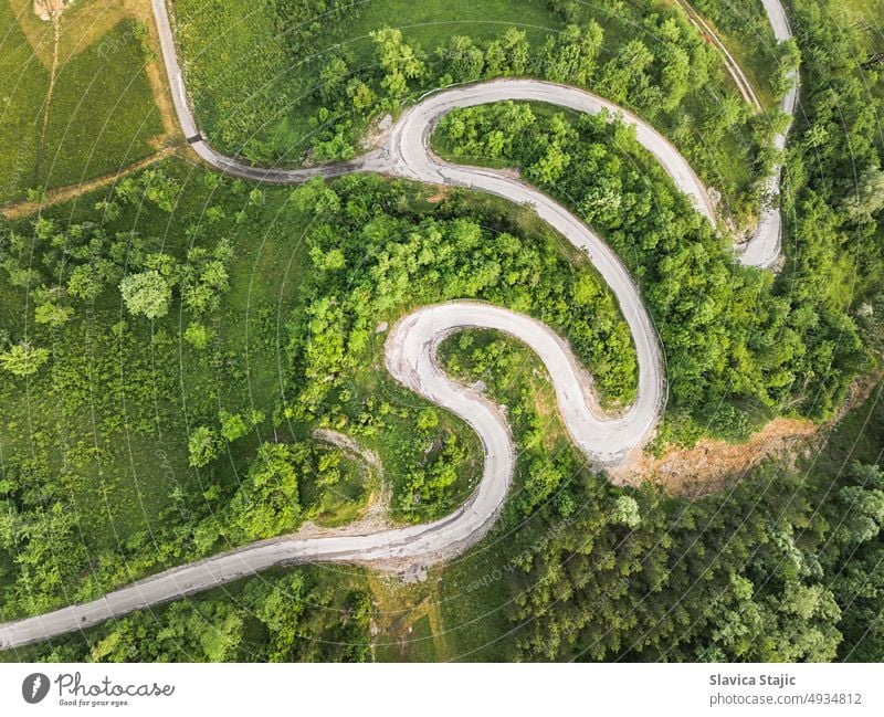Drone view of beautiful serpentine road leading through mountain landscape in summer.  Aerial photography of a road shot using a drone.  Damaged road surface