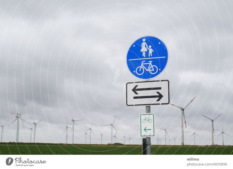 Energy filling station, with headwinds from the left and the right Wind energy plant windmills Road sign shared walkway Road marking