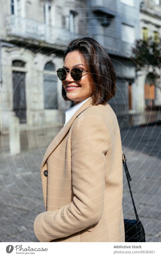Stylish woman walking on street pavement house old smart casual female style building urban pedestrian sidewalk brunette aged town stroll structure autumn coat