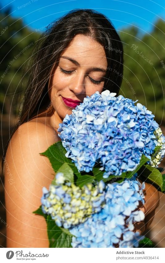 Happy alluring lady with bunch of gentle hortensia flowers in park woman hydrangea smile topless cover breast feminine positive eyes closed nature happy bouquet
