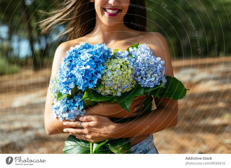 Unrecognizable happy alluring lady with bunch of gentle hortensia flowers in park woman hydrangea smile topless cover breast feminine positive eyes closed