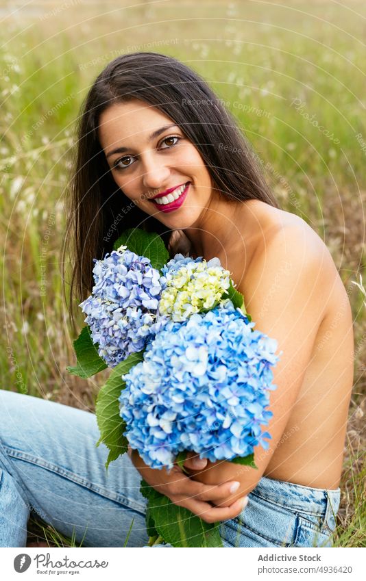 Happy alluring lady with bunch of gentle hortensia flowers in park woman hydrangea smile topless meadow cover breast feminine positive field nature happy grass