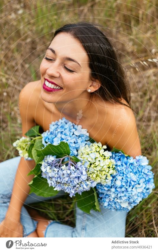 Happy alluring lady with bunch of gentle hortensia flowers in park woman hydrangea smile topless meadow cover breast feminine positive field eyes closed nature