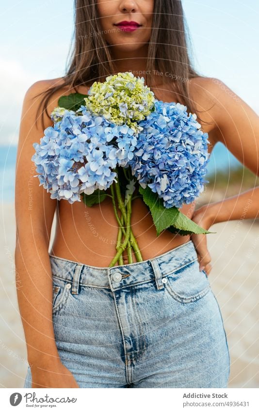 Anonymous woman covering naked breast with flowers hydrangea happy positive sea nature female young ethnic cover breast long hair dark hair topless bouquet