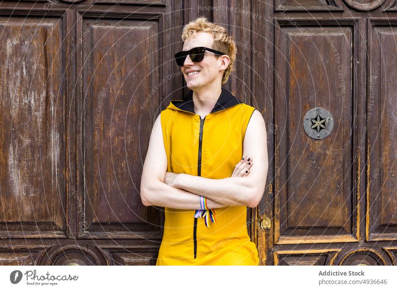 Happy non binary man against old door smile transgender lgbt happy style street portrait male young outfit sunglasses equal bracelet ribbon cheerful lgbtq