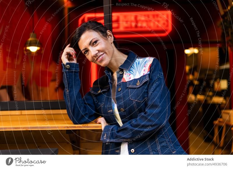 Content woman standing near cafe street city style appearance feminine urban building fashion glad positive cafeteria smile lean on hand female cheerful lady