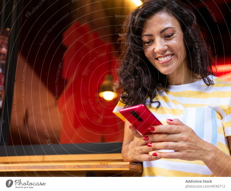 Cheerful woman browsing smartphone near cafe street city watching using conversation chat style cheerful positive happy smile delight joy appearance feminine