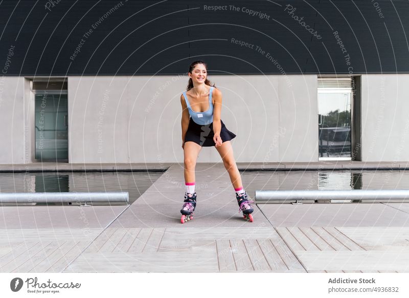 Content fit lady practicing rollerblading in city woman blade self assured style confident smile activity positive happy female young dark hair brunette