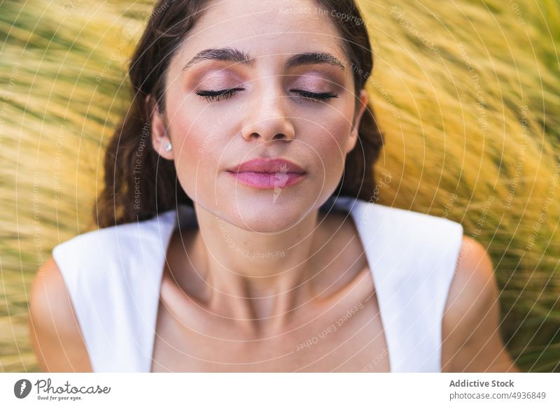 Calm lady lying on dry grassy meadow with closed eyes woman eyes closed countryside grace model calm tranquil peaceful style female young makeup appearance