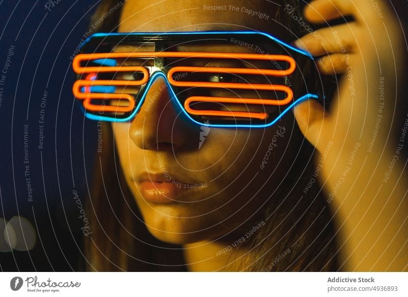 Young woman in futuristic glasses at night dark style appearance neon portrait cyberpunk female dark hair young personality human face gaze brunette dim obscure