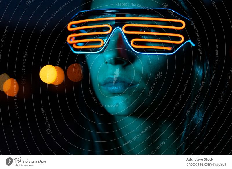 Young woman in futuristic glasses at night dark style appearance neon portrait cyberpunk female dark hair young personality human face gaze brunette dim obscure