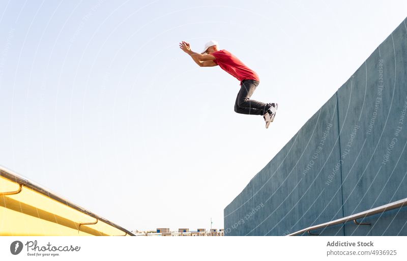 Energetic man jumping from building and showing parkour stunt trick edge energy hipster city male extreme urban active activity perform moment above ground
