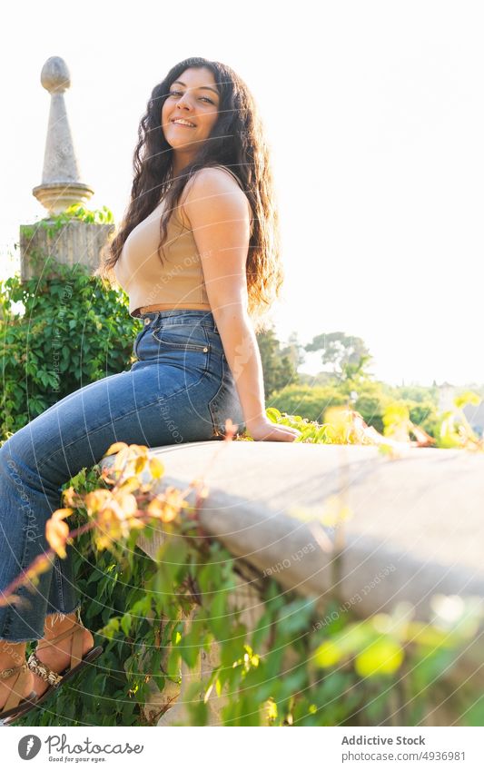 Woman Looking at camera While Sitting At Park Smiling Sky Beautiful Lifestyle Curly Hair Sunlight Leisure Smile Attractive Candid Contemplation Casual Clothes