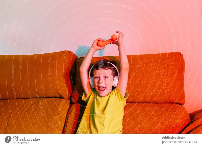 Cheerful boy celebrating victory while playing video game kid win videogame entertain amusement triumph pastime arms raised living room excited happy positive