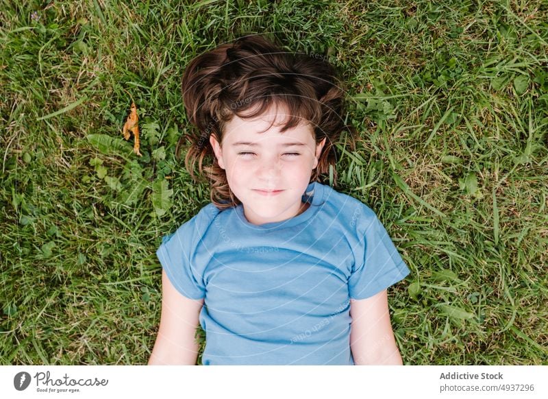 Girl with eyes closed lying on grass girl lawn park summer weekend casual child childhood little pastime recreation season field tender individuality nature