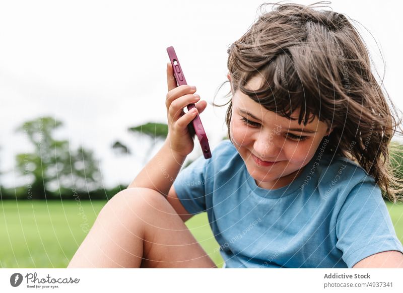 Happy girl speaking on smartphone in park lawn summer weekend cheerful barefoot delight phone call happy talk glad communicate childhood device gadget smile