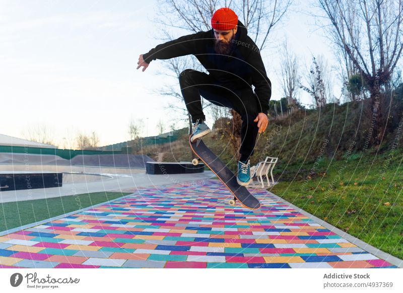 Man jumping with skateboard in skate park man skater trick stunt perform hipster hobby male above ground energy pavement colorful autumn fall activity skill
