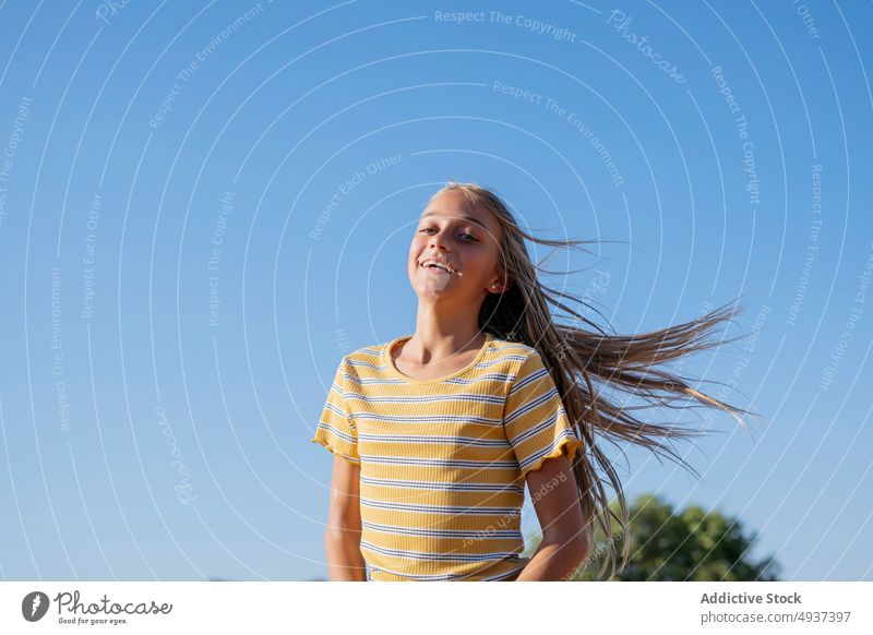 Content girl with flying hair teenage street appearance city carefree style smile wind glad blue sky summer positive portrait long hair cheerful happy