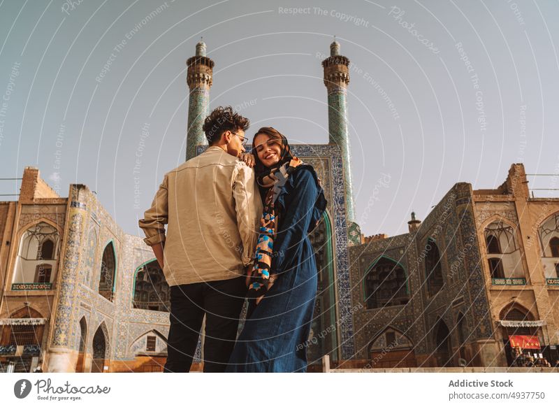 Loving couple of travelers standing near old mosque during sightseeing trip romantic relationship together love architecture tourism worship cuddle girlfriend