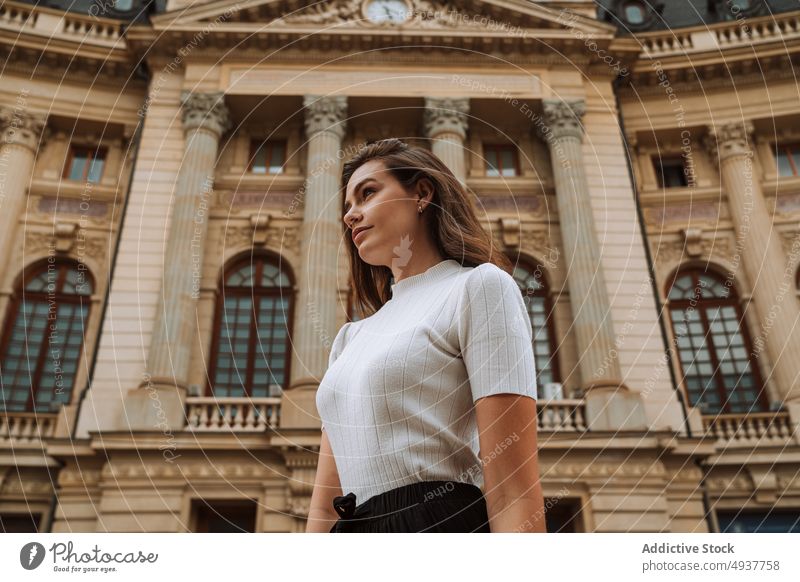 Calm young woman sightseeing in old city district trip tourist architecture building travel facade traveler ancient exterior female brunette casual vacation