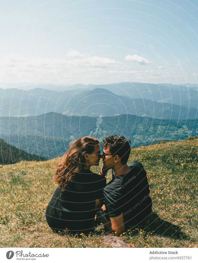 Loving couple embracing on grassy hill in mountainous valley kiss love nature travel trip romantic together affection embrace picturesque viewpoint boyfriend