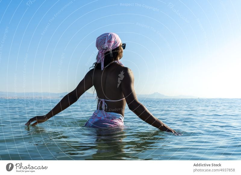 Black woman standing in sea water resort vacation swimsuit summer blue sky headscarf female morning black african american ethnic swimwear headband ocean