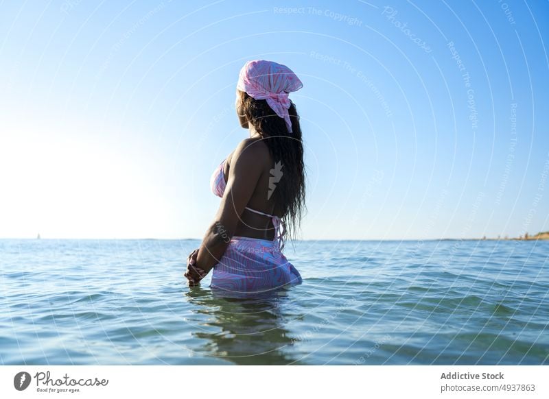 Black woman standing in sea water resort vacation swimsuit summer blue sky headscarf female morning black african american ethnic swimwear headband ocean
