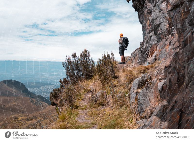 Traveler with backpack standing on top of mountain man traveler edge hiker observe valley adventure rocky male trekking cliff highland explore viewpoint admire