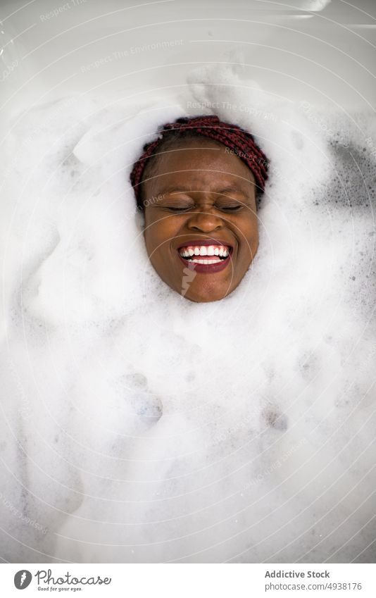 Happy African American female in foamy water woman bathtub soap laugh spa weekend skin care young black african american ethnic cheerful happy hygiene wellness