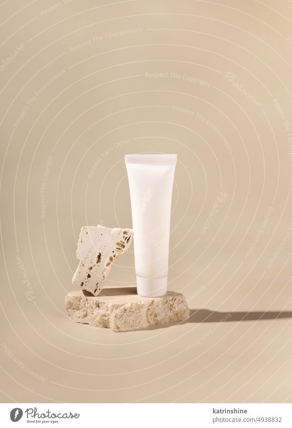 White plastic cream tube on travertine stone on light yellow close up, Mockup mockup white pastel negative space copy space Brand packaging natural cosmetics