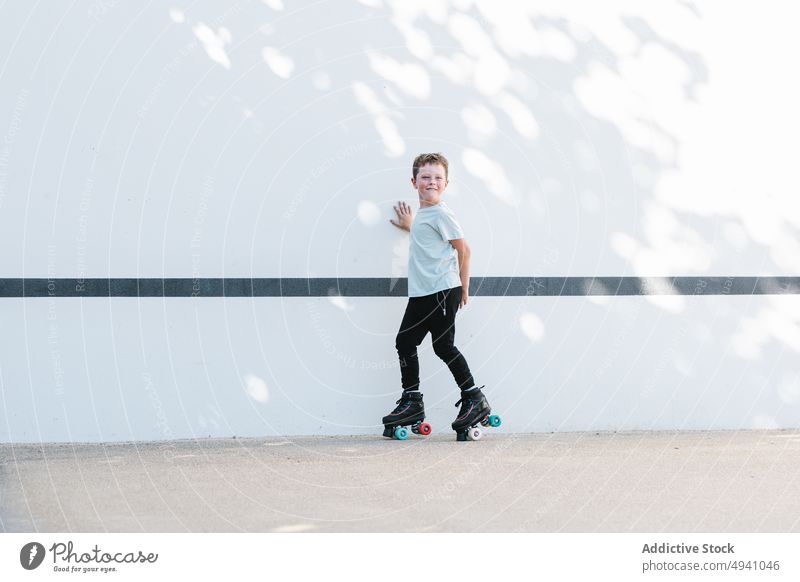 Happy boy riding roller skates on street ride summer happy weekend activity hobby daytime smile urban kid pastime casual childhood free time practice lifestyle