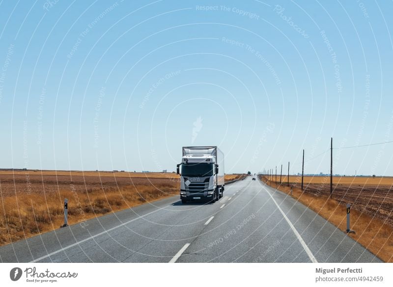 Refrigerator truck driving on a straight road, with a flat horizon and a clear sky. transportation freight nature perspective traffic trailer landscape logistic