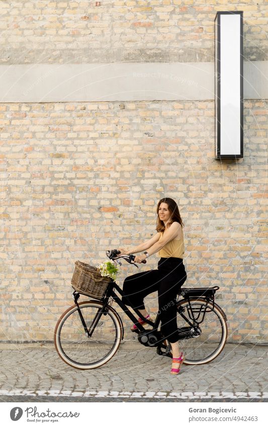 Woman with flowers in the basket of electric bike lifestyle outdoor riding city street urban transport activity adult beautiful bicycle blank caucasian