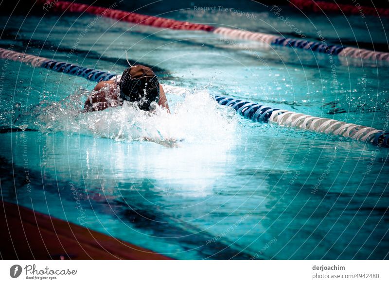 A girl doing sports swimming . With her head half in the splashing water, she tries to reach the finish line with powerful strokes. Swimming & Bathing Water