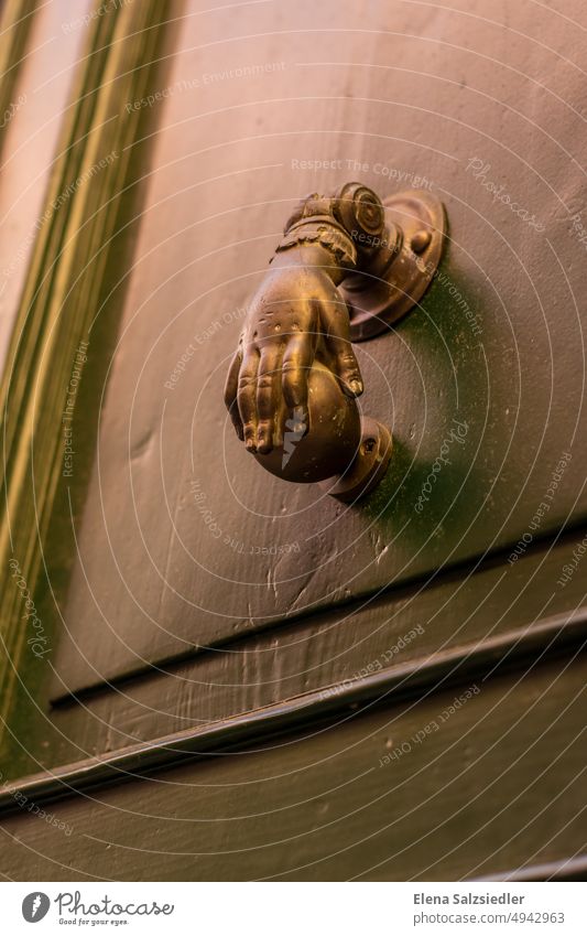 Vintage door knocker in an Italian old town. Knocker Hand Ancient vintage Brass Brass door knocker door handle Fist Sphere Old Entrance Door handle