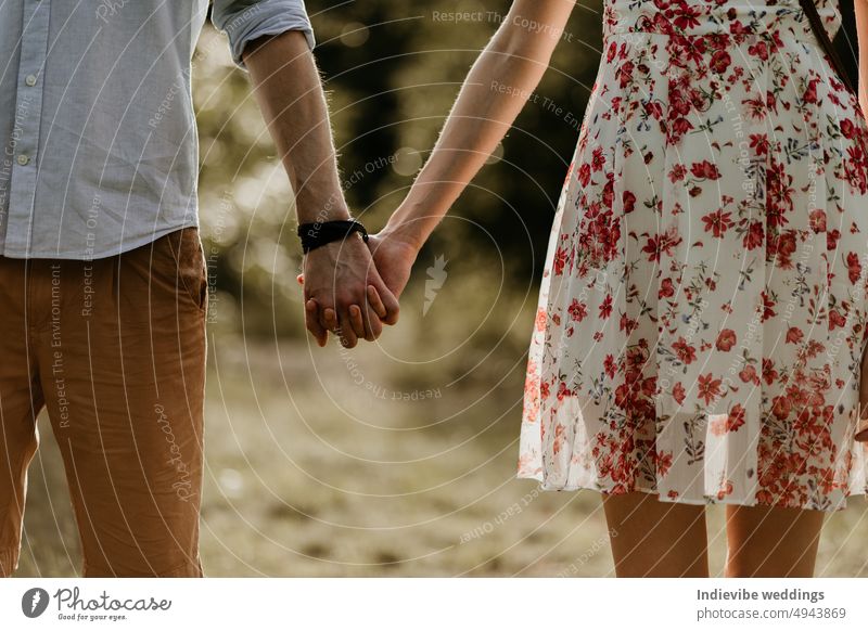 A couple in love is standing next to each other and holding hands. Man and woman are wearing summer dress and clothes. Outdoor date. Trendy fashionable clothing.