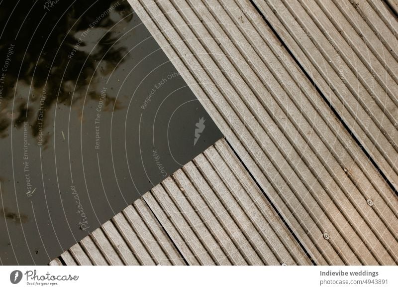 A wooden deck detail over a pond. Abstract architectural pattern detail of a timber decking in the park. Modern minimal concept, copy space. Parallel lines.