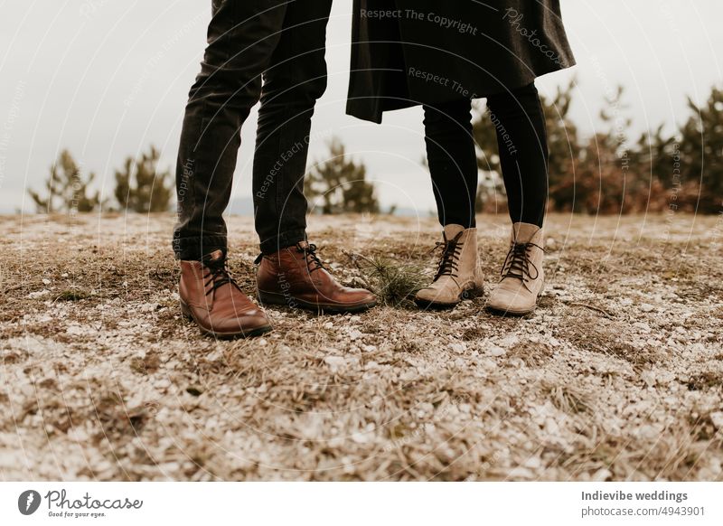 Closeup of feet of a couple in love. Autumn outdoor date. The man is standing, wearing brown leather boots, the woman is wearing beige shoes. Outdoor fashion concept.