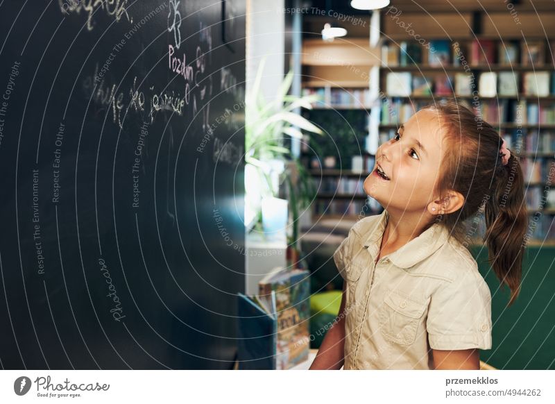 Little girl writing on blackboard. Smart student put solve on chalkboard. Back to school. Child having class. Schoolgirl learning at primary school back child