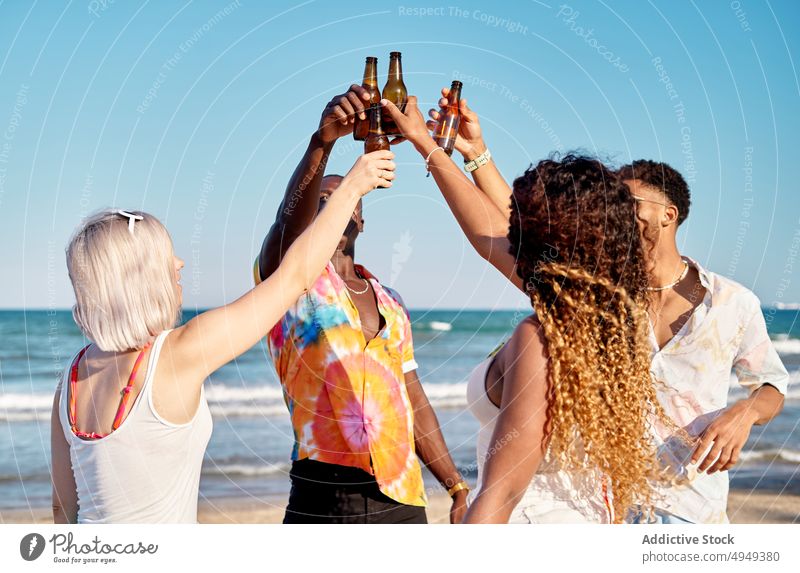 Happy multiethnic friends clinking beer bottles during summer party people toast smile together drink happy hangout occasion celebrate young multiracial diverse
