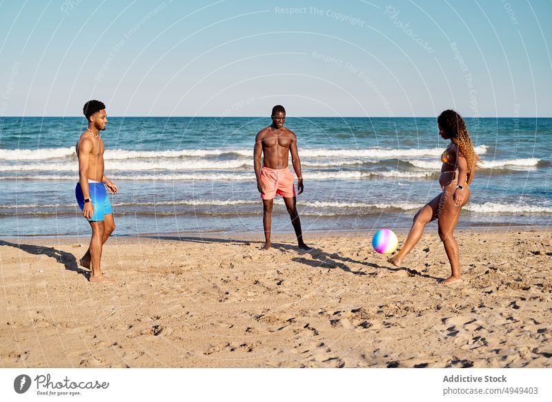 Diverse friends playing with beach ball together sea hit fly weekend summer men women young diverse multiracial multiethnic black african american activity sand