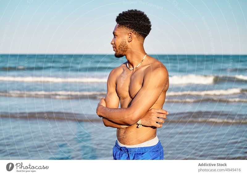 Black young male tourist standing near sea man beach summer weekend curly hair resort vacation thoughtful holiday portrait coast shore tourism activity water