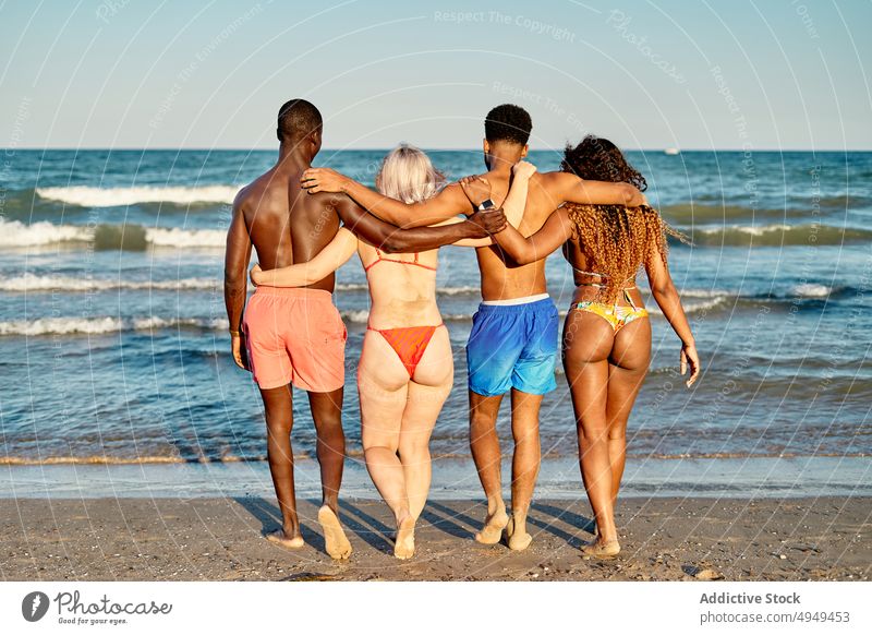 Anonymous merry diverse friends hugging on beach weekend summer walk together happy vacation resort men women embrace girlfriend boyfriend positive shore