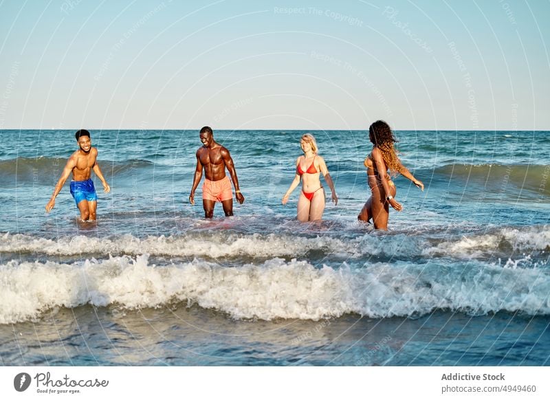Multiracial friends playing in sea water summer weekend beach together wave men women diverse multiracial multiethnic black african american swimsuit smile