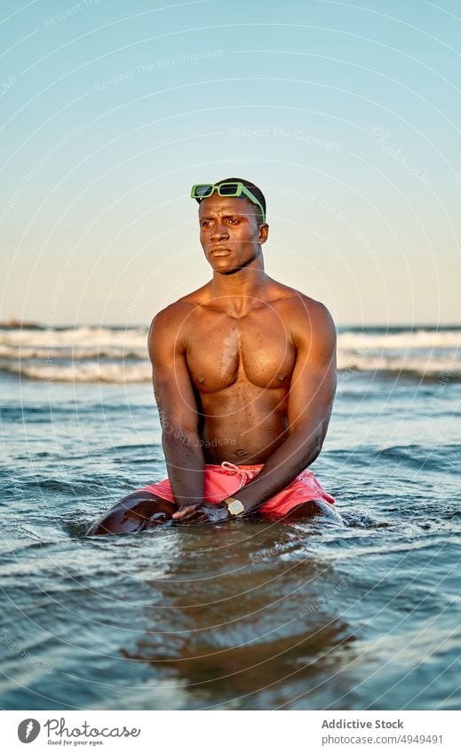 Pensive shirtless black man in sea water weekend summer adjust sunglasses vacation clean male muscular young african american ethnic tourist recreation fit
