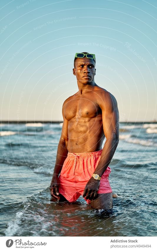 Pensive shirtless black man in sea water weekend summer adjust sunglasses vacation clean stand male muscular young african american ethnic tourist recreation